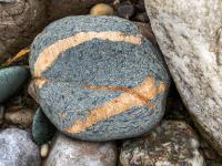 Grauer Stein mit breiten rötlichen Maserungen
